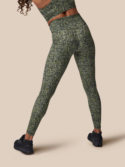Person wearing green patterned leggings on a beige background