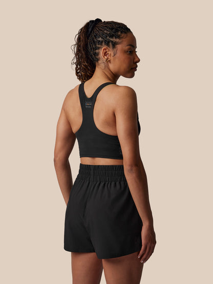Woman wearing a black athletic outfit on a beige background