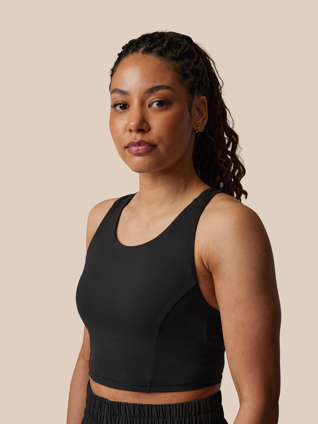 Woman wearing a black sports bra against a beige background