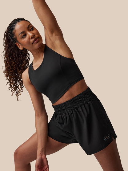 Woman in black athletic wear posing against a beige background