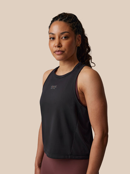 Woman wearing a black tank top with a beige background