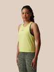 Woman wearing a yellow tank top and patterned pants on a beige background