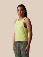 Woman wearing a yellow tank top and patterned pants on a beige background