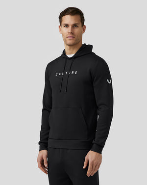Front view of a man in a black Flex Hoodie with bold white branding on the chest, drawstring hood and front pocket.