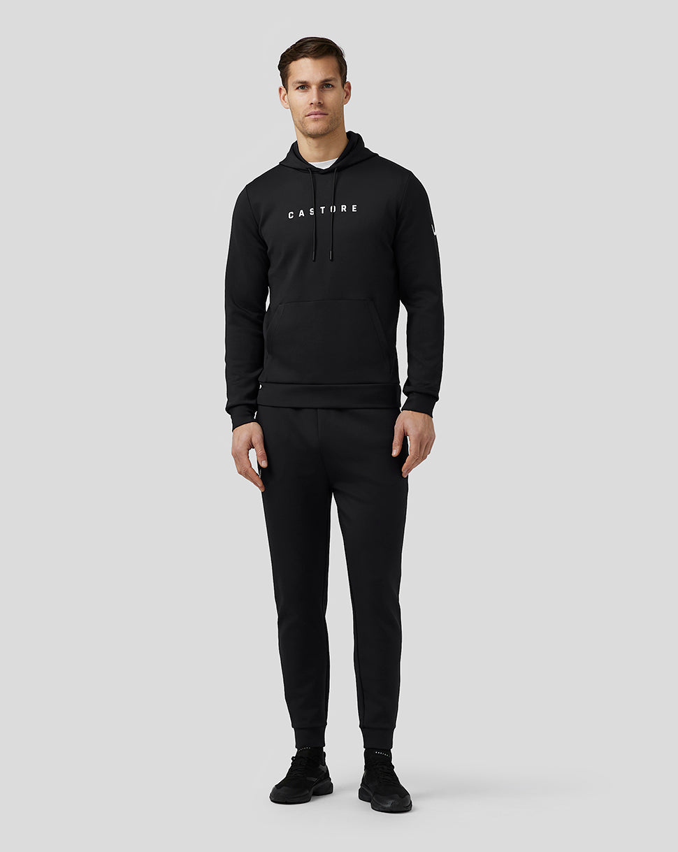Male model wearing black Castore Flex Hoodie with front logo, drawstring hood and large front pocket.
