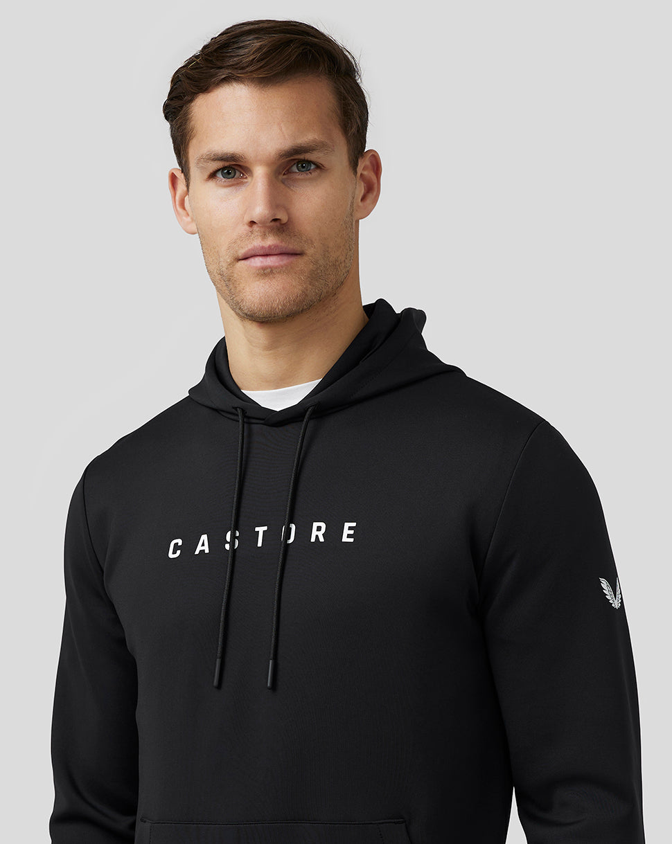 Close-up of a man wearing a black Flex Hoodie with CASTORE branding on the chest and visible drawstrings.