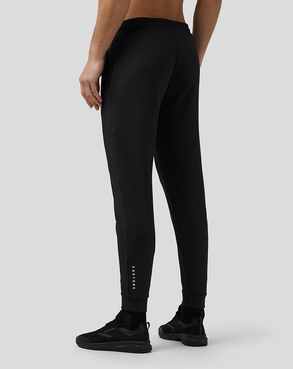 Back view of a man in black Flex Joggers with elastic cuffs and CASTORE lettering along the lower leg.