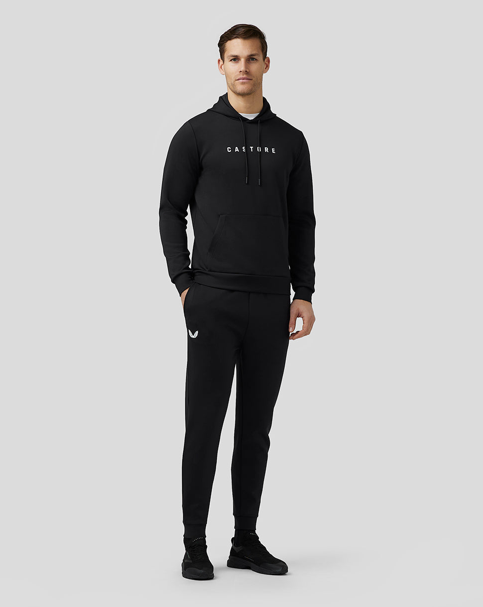Full body shot of a male model in black Castore Flex Joggers with bold side branding