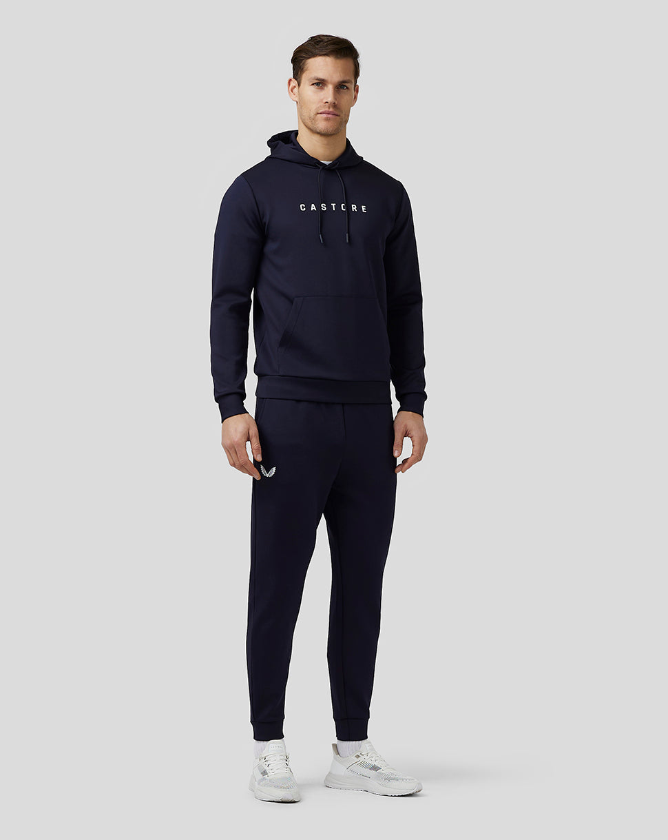 Male model in navy Castore Flex Joggers with hoodie, front view.