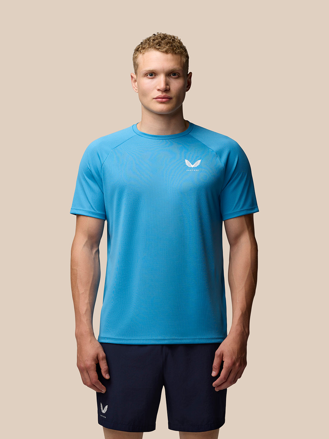 Male model in Corn Blue Adapt Training T-Shirt with navy shorts, Castore branding on chest.