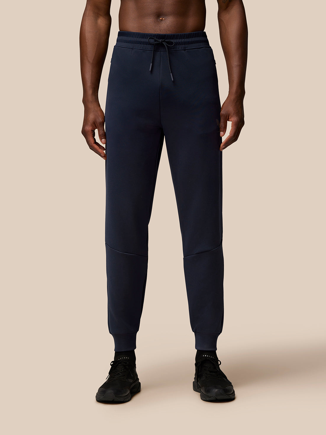 Front view of navy Flex Lifestyle Joggers on a male model with a drawstring waistband, cuffed ankles, and external pockets.