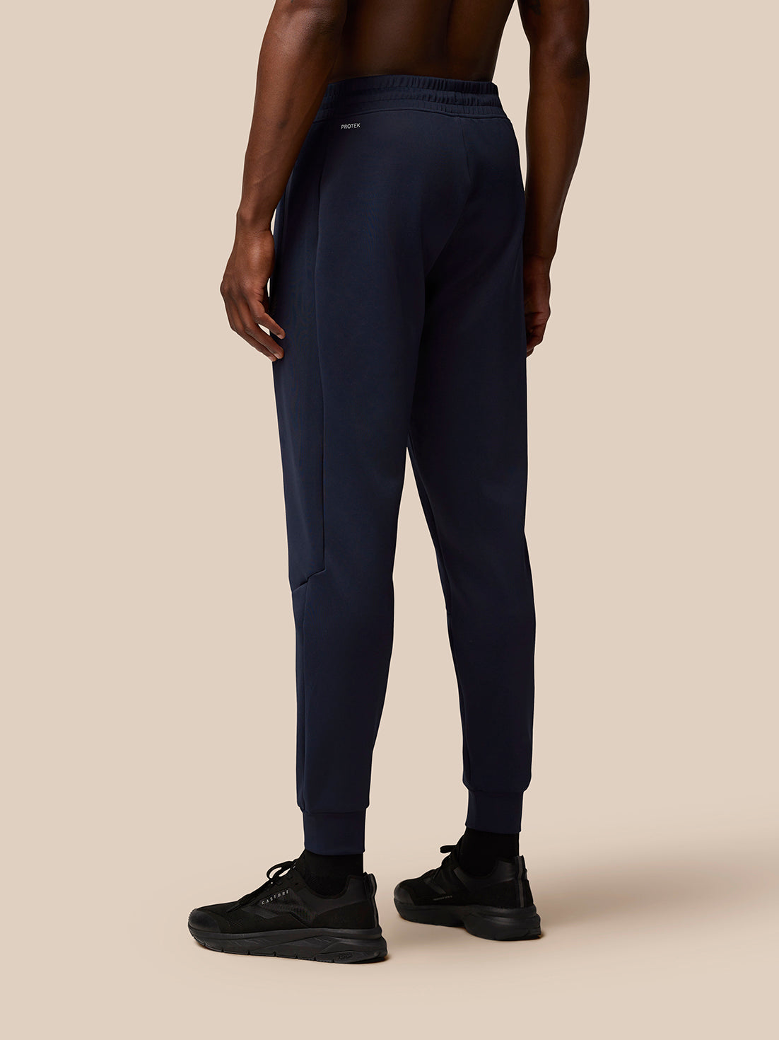 Back view of navy Flex Lifestyle Joggers on a male model, waistband with Protek branding at the rear.