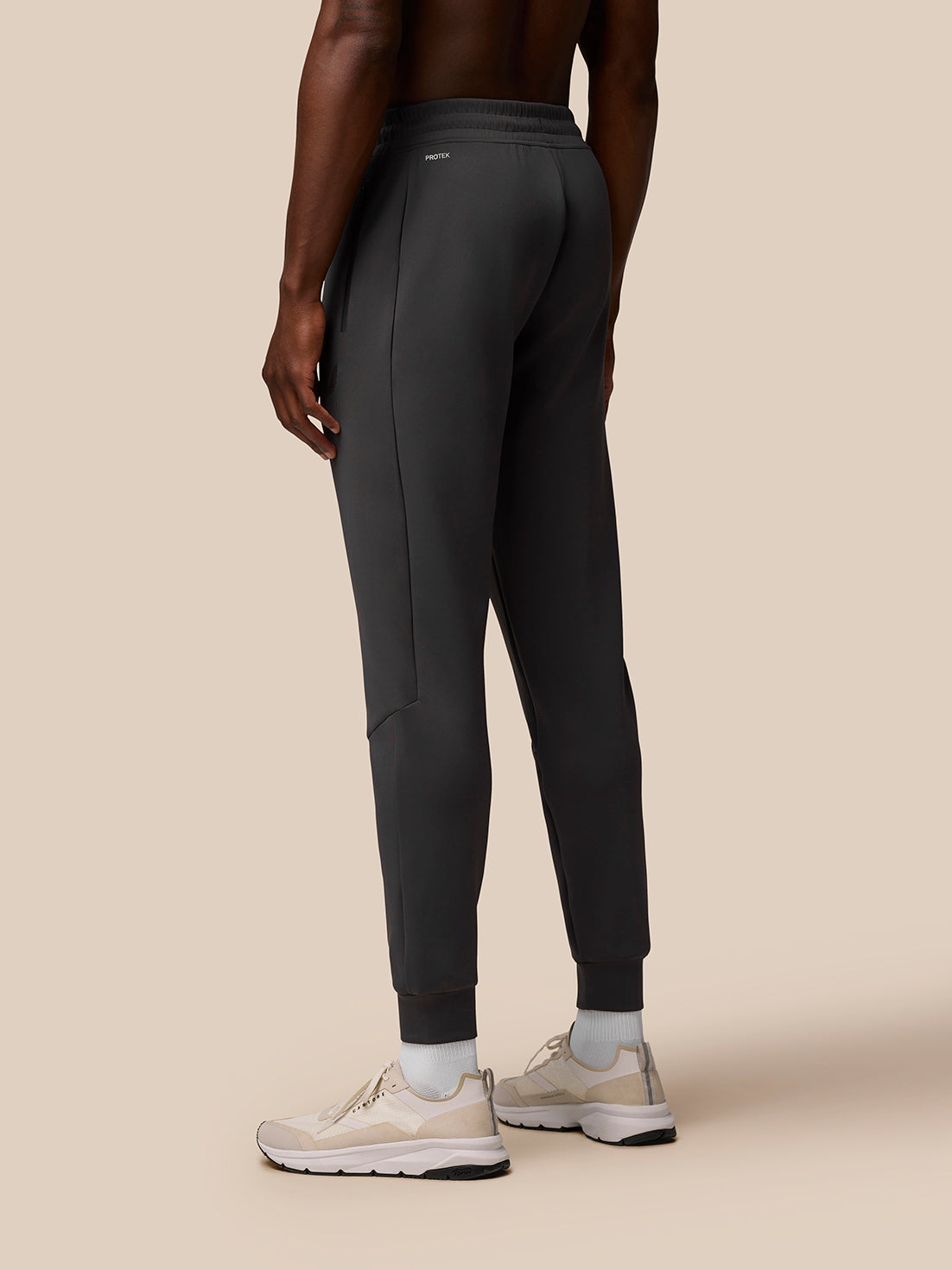 Back view of a man wearing charcoal Flex Lifestyle Joggers with an elasticated drawcord waistband and Protek branding.