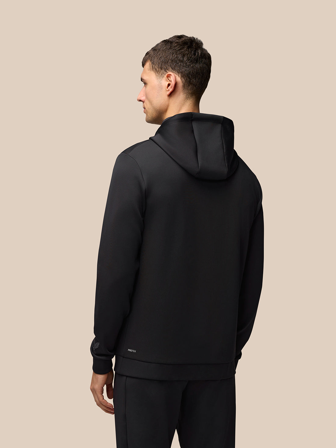 Back view of a man wearing a black Flex Lifestyle Hoodie with the hood resting on his shoulders