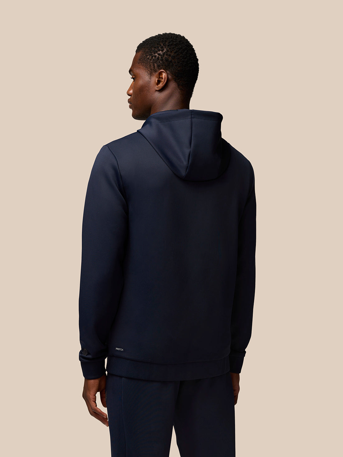 Back view of a man wearing navy Flex Lifestyle Hoodie with hood down and Protek branding at the lower back