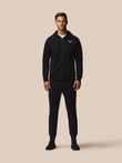 Male model in black zip hoodie with logo and matching joggers from the Travel Lifestyle collection.