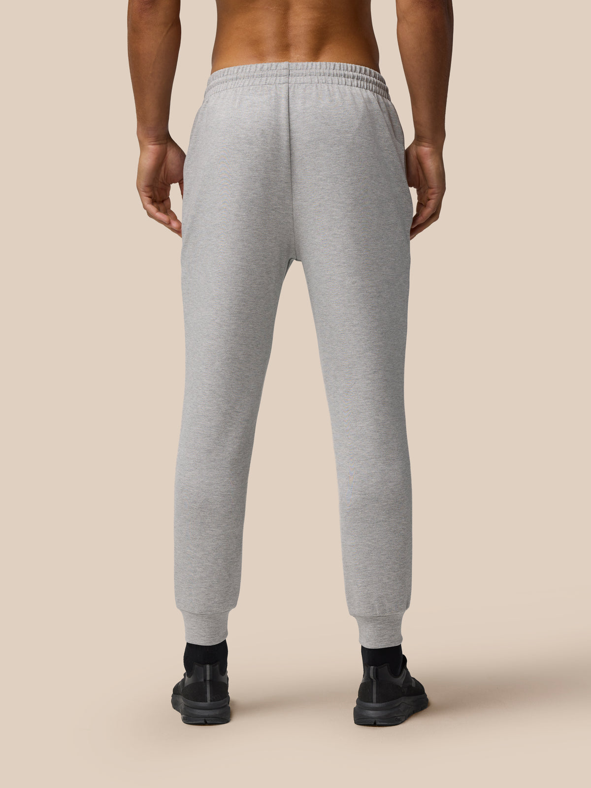 Back view of male model wearing grey marl Travel Lifestyle Joggers with a tapered fit, elastic waistband and cuffed hems