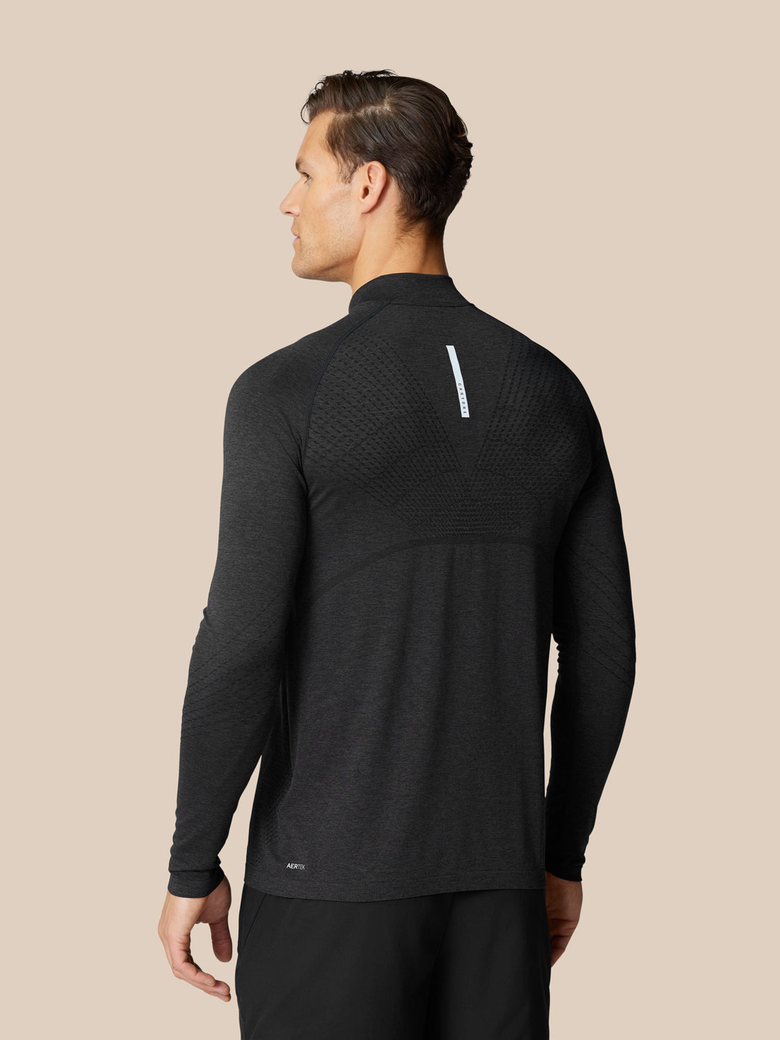 Back view of dark Flow Training Top showing knitted back panels for airflow.