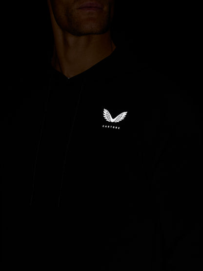 Close-up of white Castore wing logo on the chest of a black Travel Lifestyle Hoodie