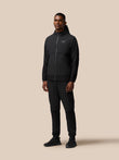 Male model wearing black Flex Winterised woven hooded jacket with zip and matching joggers