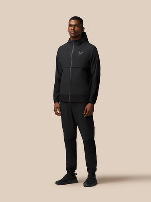 Male model wearing black Flex Winterised woven hooded jacket with zip and matching joggers