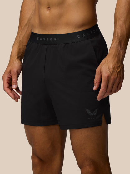 Black athletic shorts with brand logo on a beige background