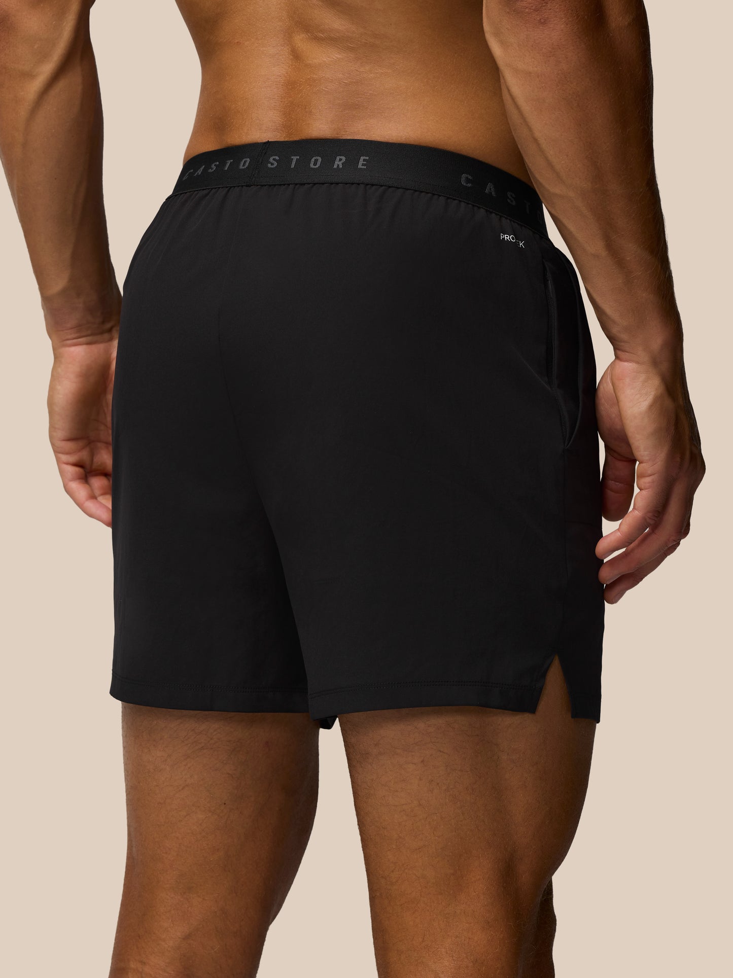 Person wearing black athletic shorts on a beige background