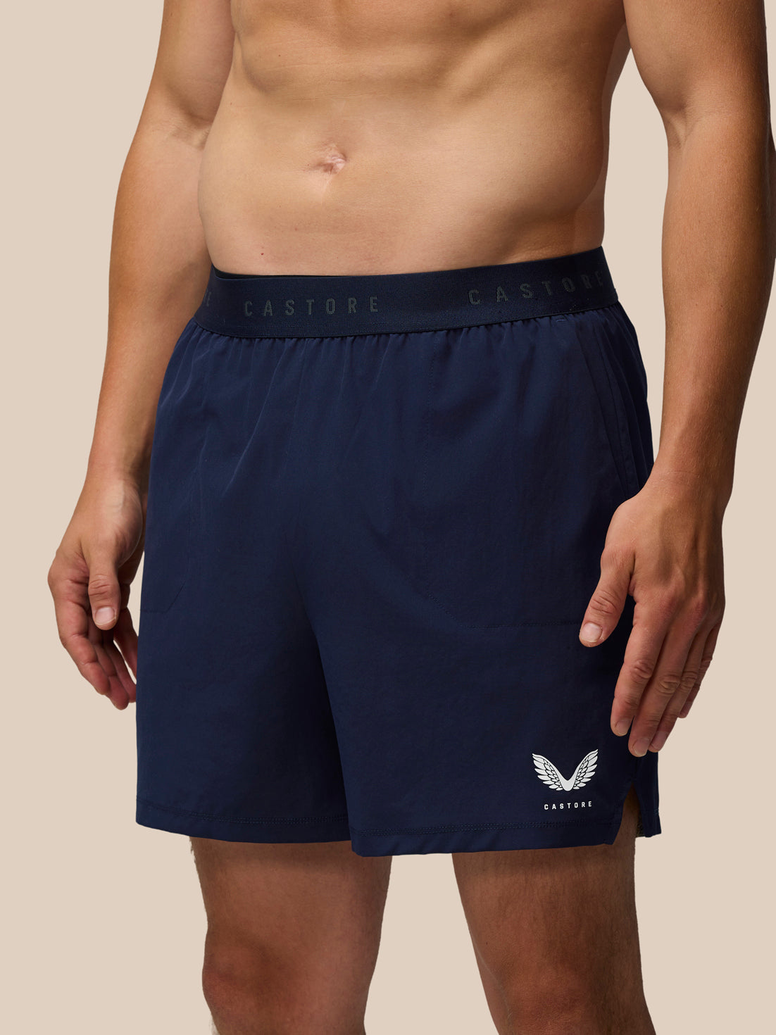 Male model wearing navy Adapt Training 5-Inch Shorts with branded elastic waistband and Castore logo on the leg