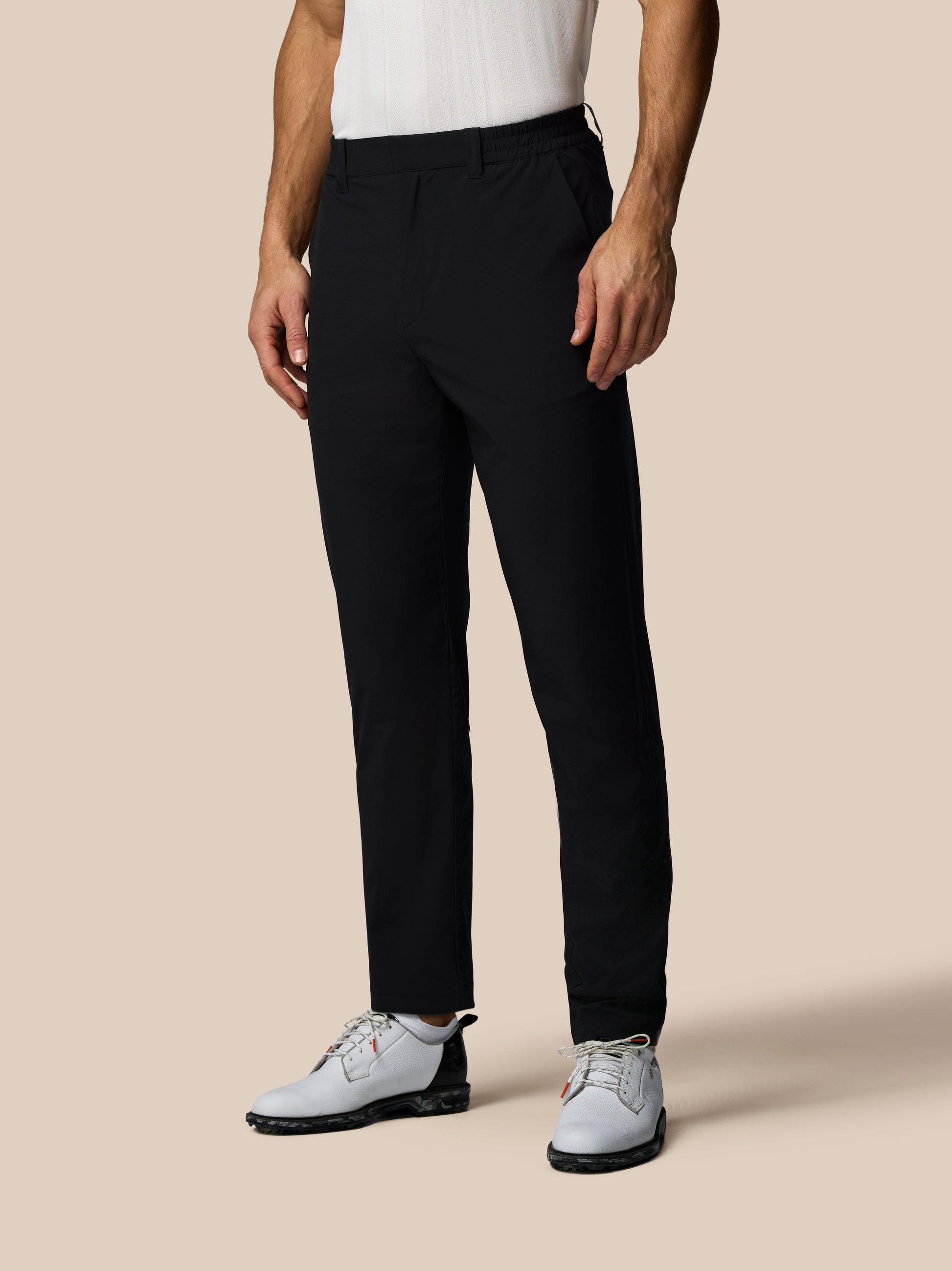 Person wearing black pants and white shoes on a beige background