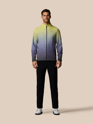 Man wearing a gradient jacket and black pants on a beige background