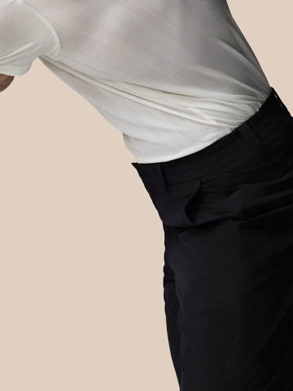 Person wearing a white shirt and black pants on a beige background