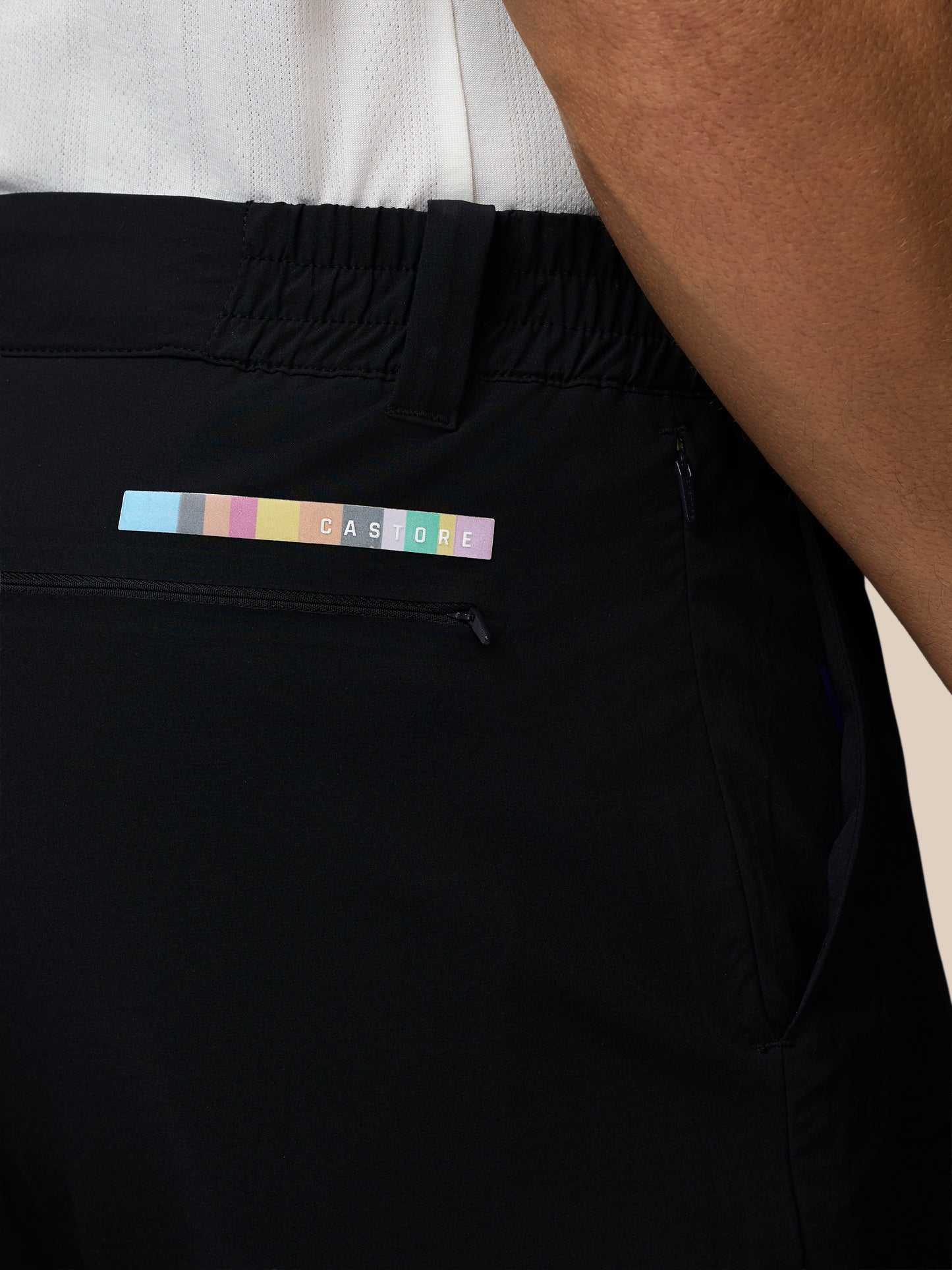 Black pants with a colorful label on the pocket, worn by a person.