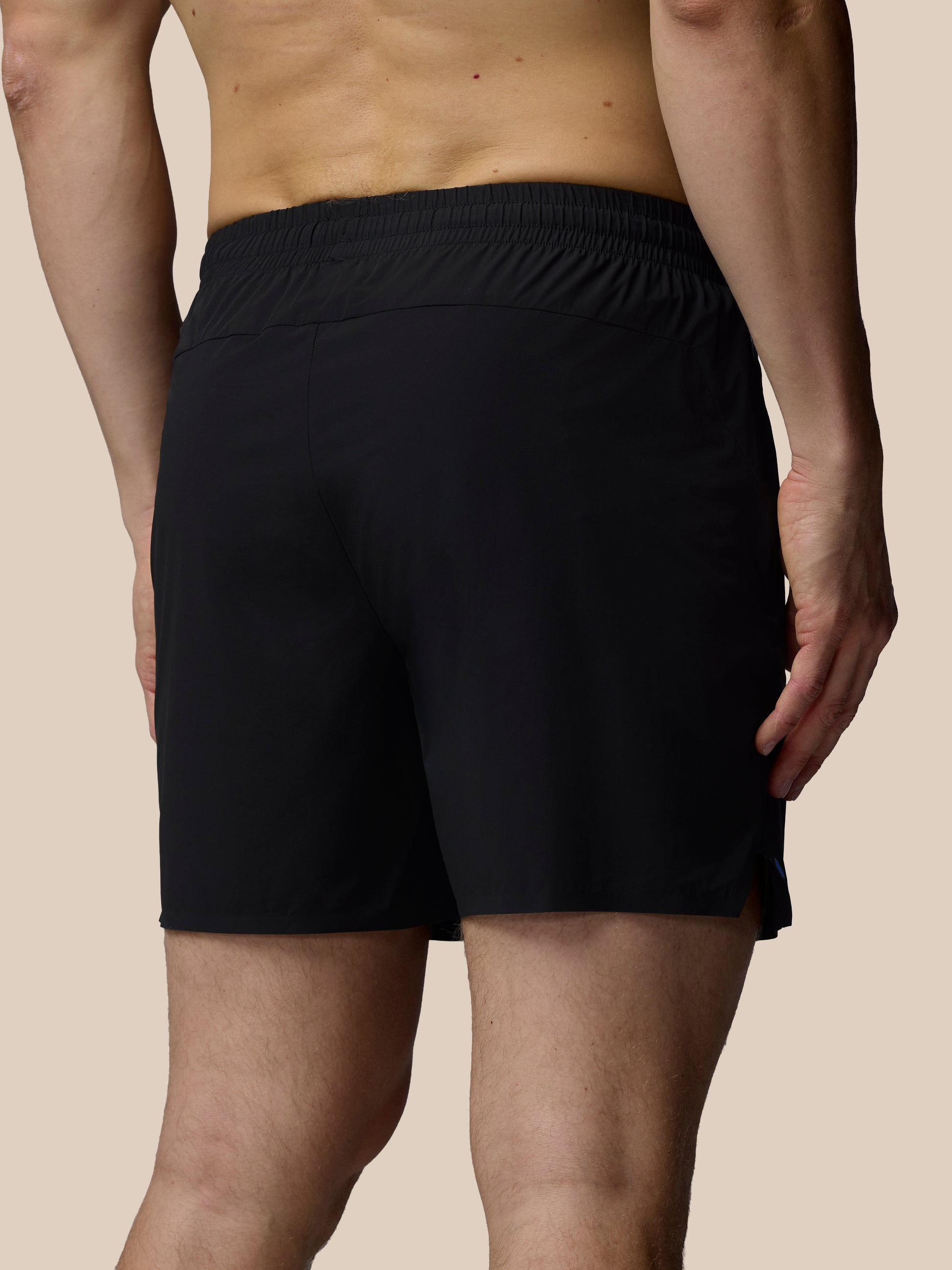 Person wearing black shorts on a beige background