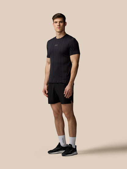 Man wearing a black t-shirt and shorts on a beige background