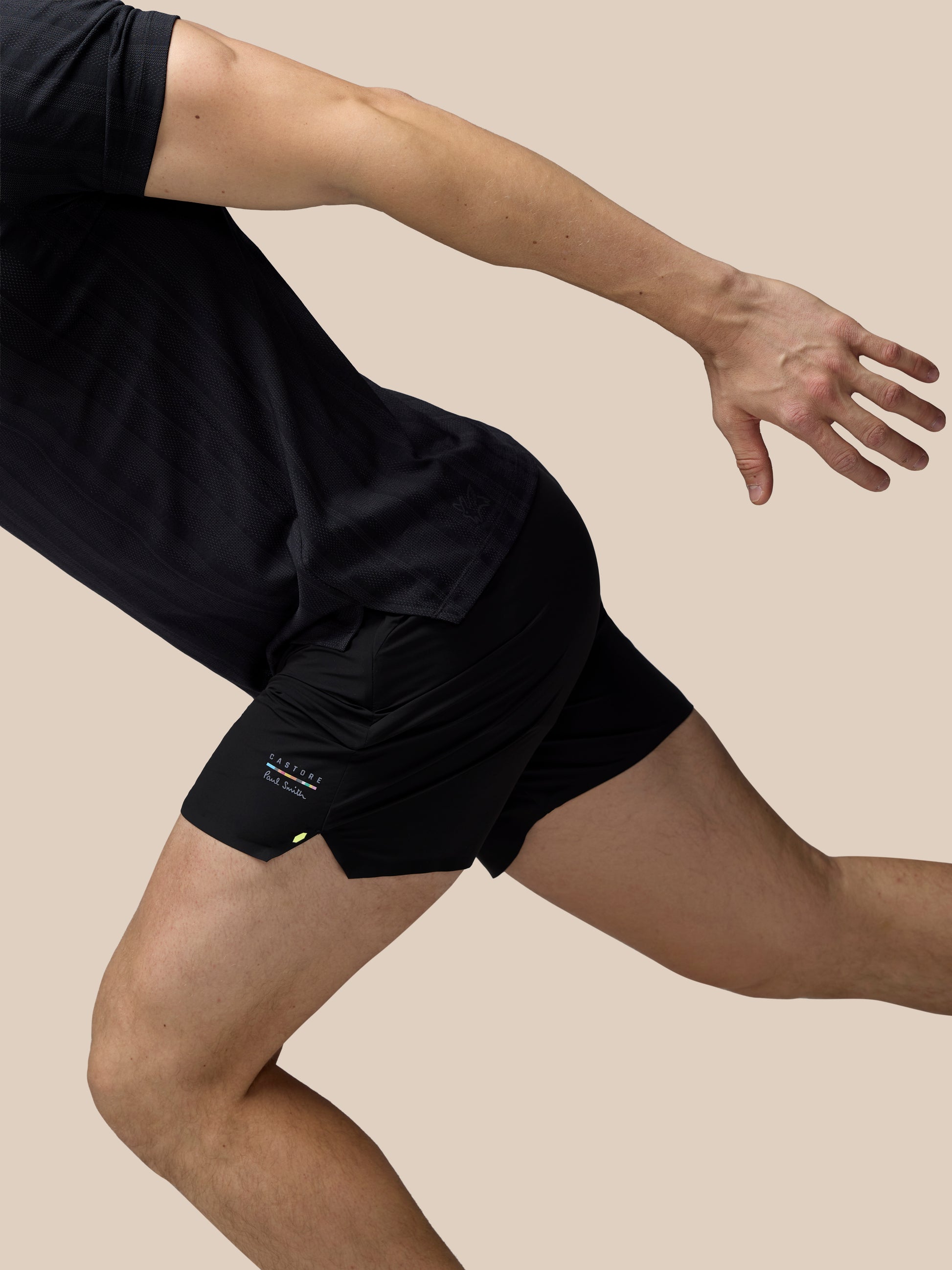Person wearing black athletic shorts on a beige background