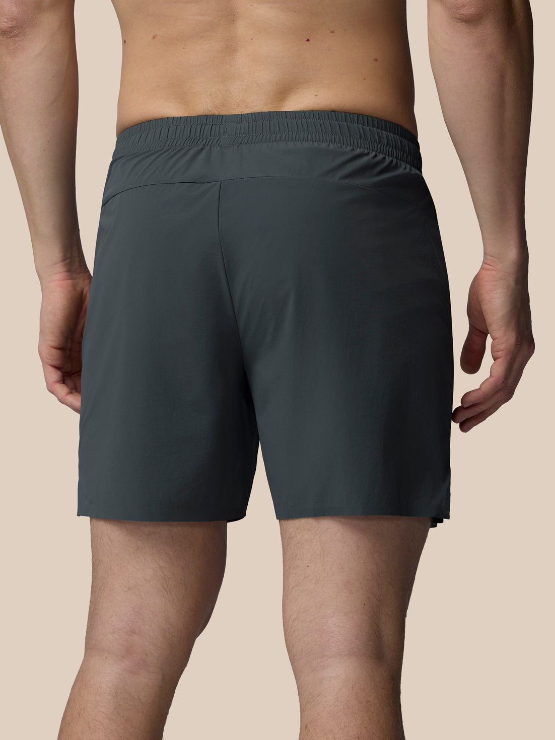 Person wearing dark gray shorts on a beige background