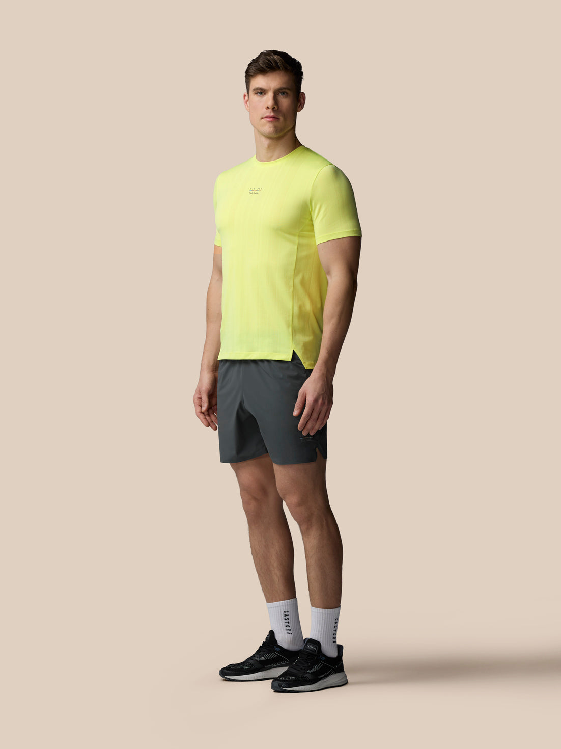 Man wearing a bright yellow athletic shirt and gray shorts on a beige background