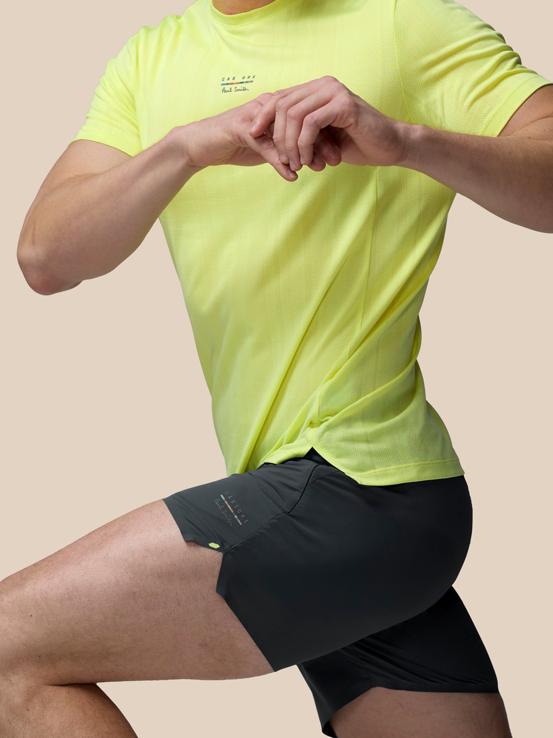 Person wearing a bright yellow athletic shirt and black shorts on a beige background