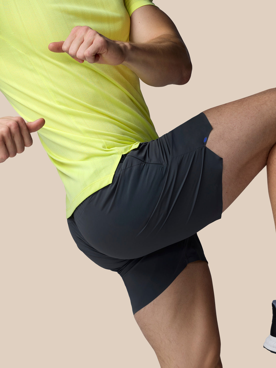 Person wearing a bright yellow shirt and black shorts on a beige background