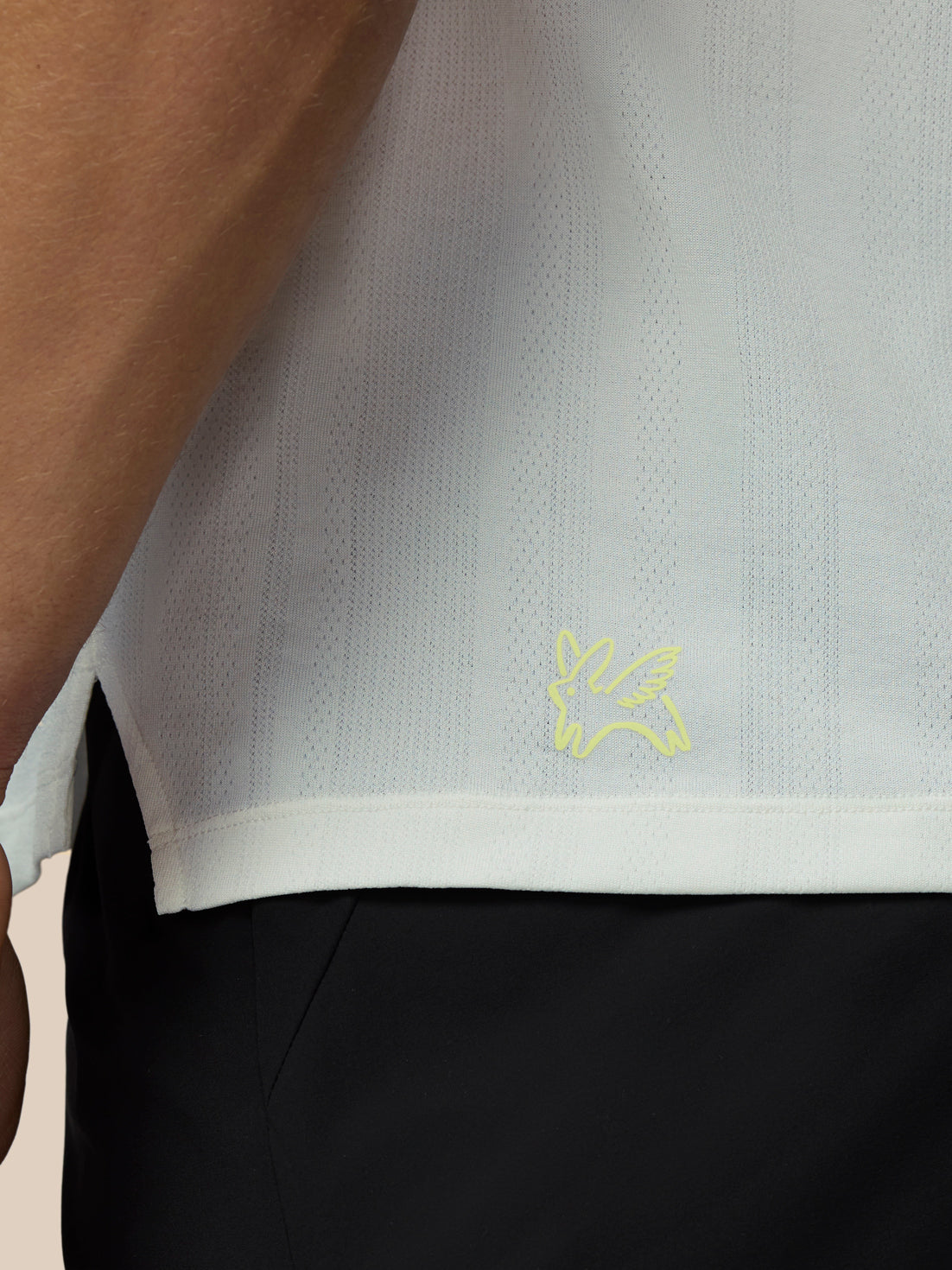 Close-up of a white shirt with a logo, worn by a person.