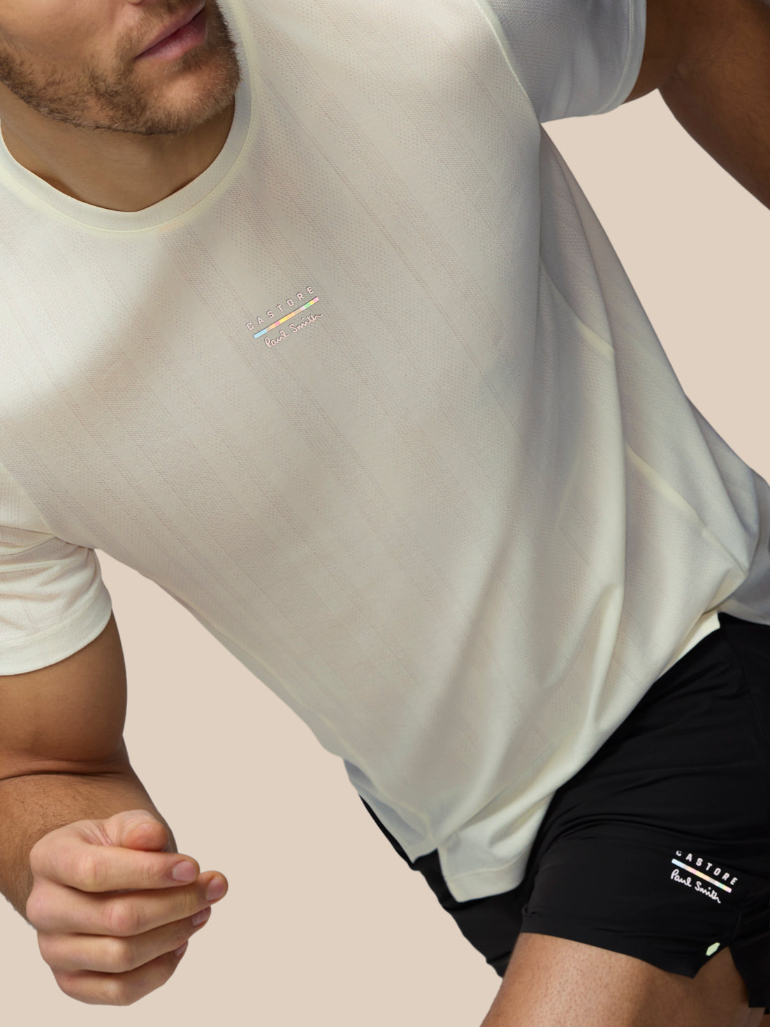 Person wearing a white t-shirt with a logo on a beige background