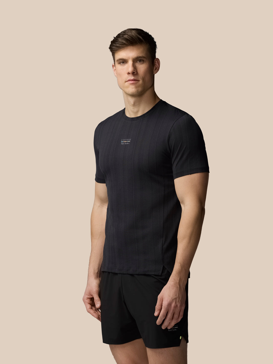 Man wearing a black t-shirt and shorts on a beige background