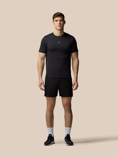 Man wearing a black t-shirt and shorts on a beige background