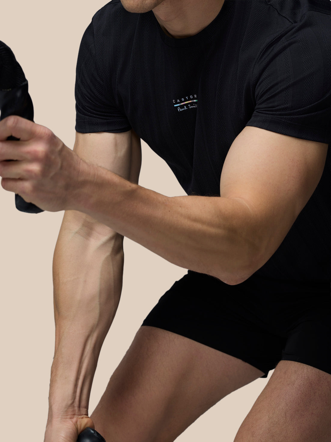 Person wearing a black t-shirt and shorts on a beige background