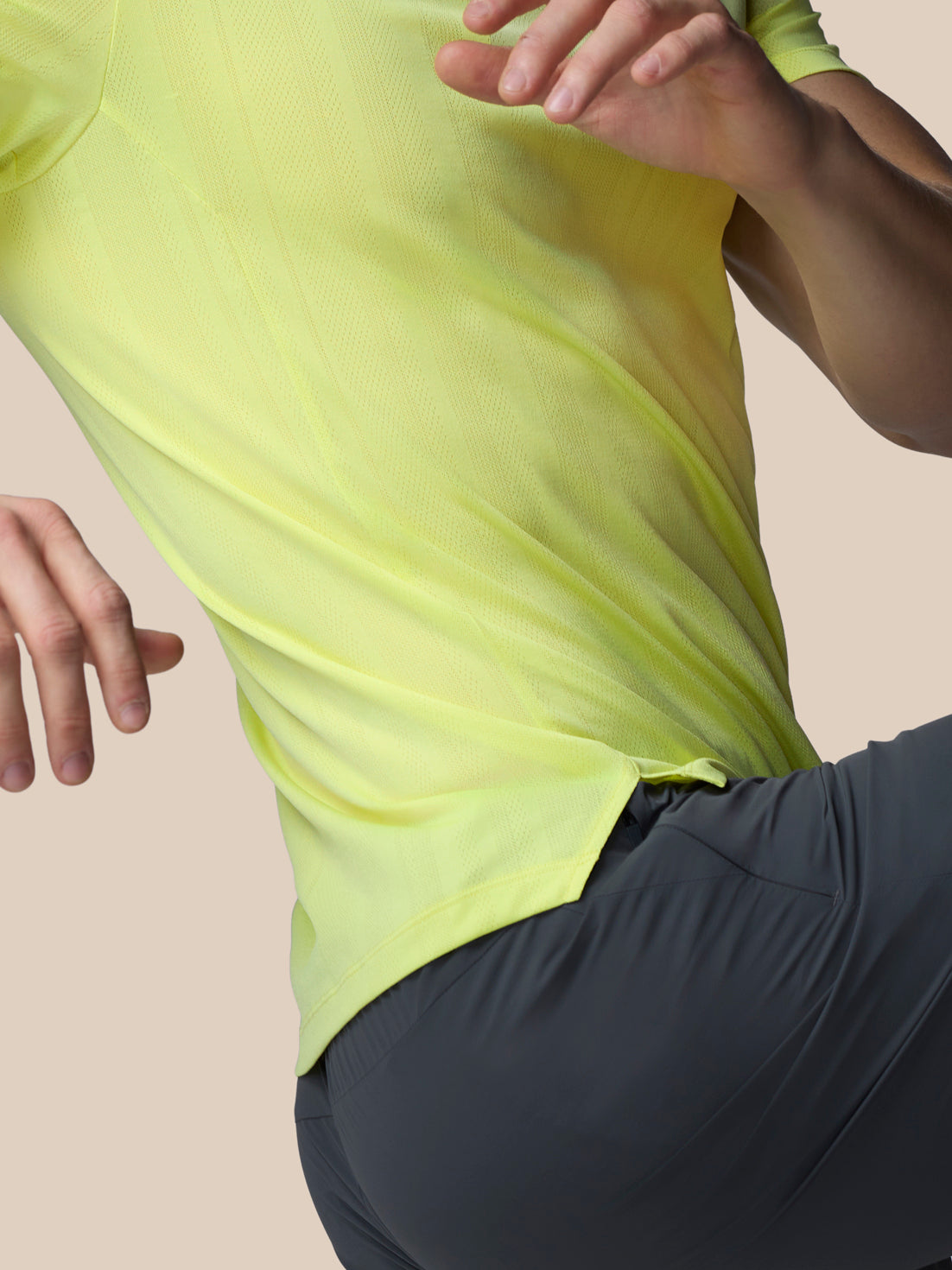 Person wearing a bright yellow long-sleeve shirt and dark gray pants on a beige background