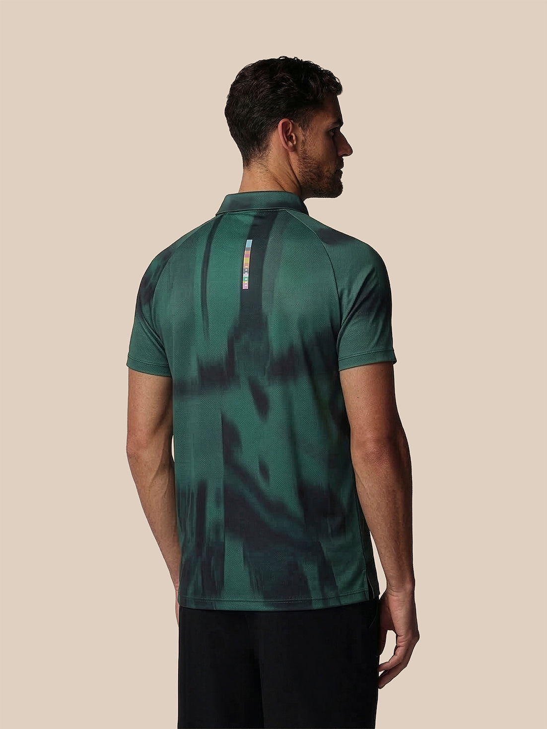 Man wearing a green camouflage-patterned polo shirt on a beige background