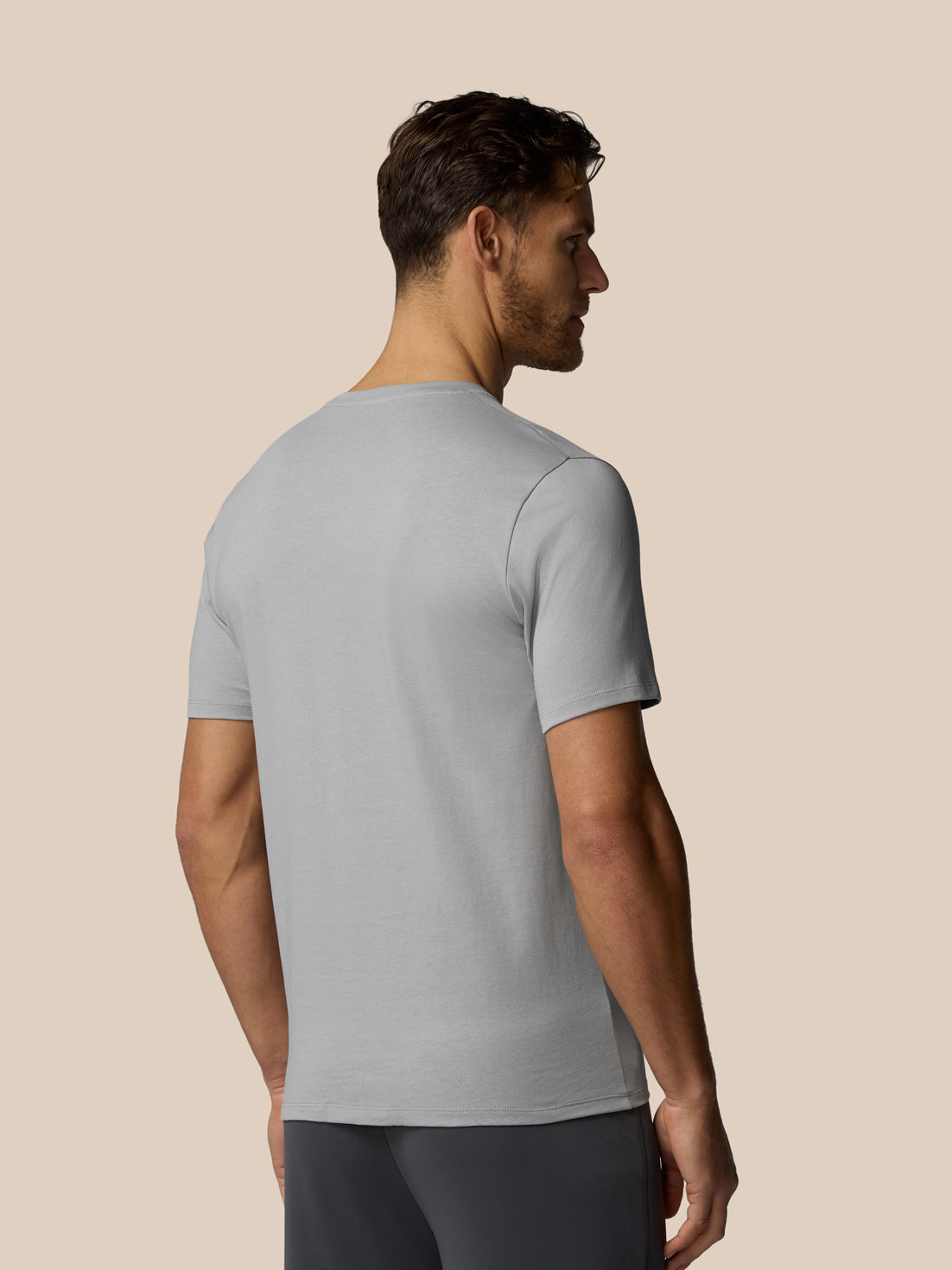 Man wearing a light gray t-shirt against a beige background