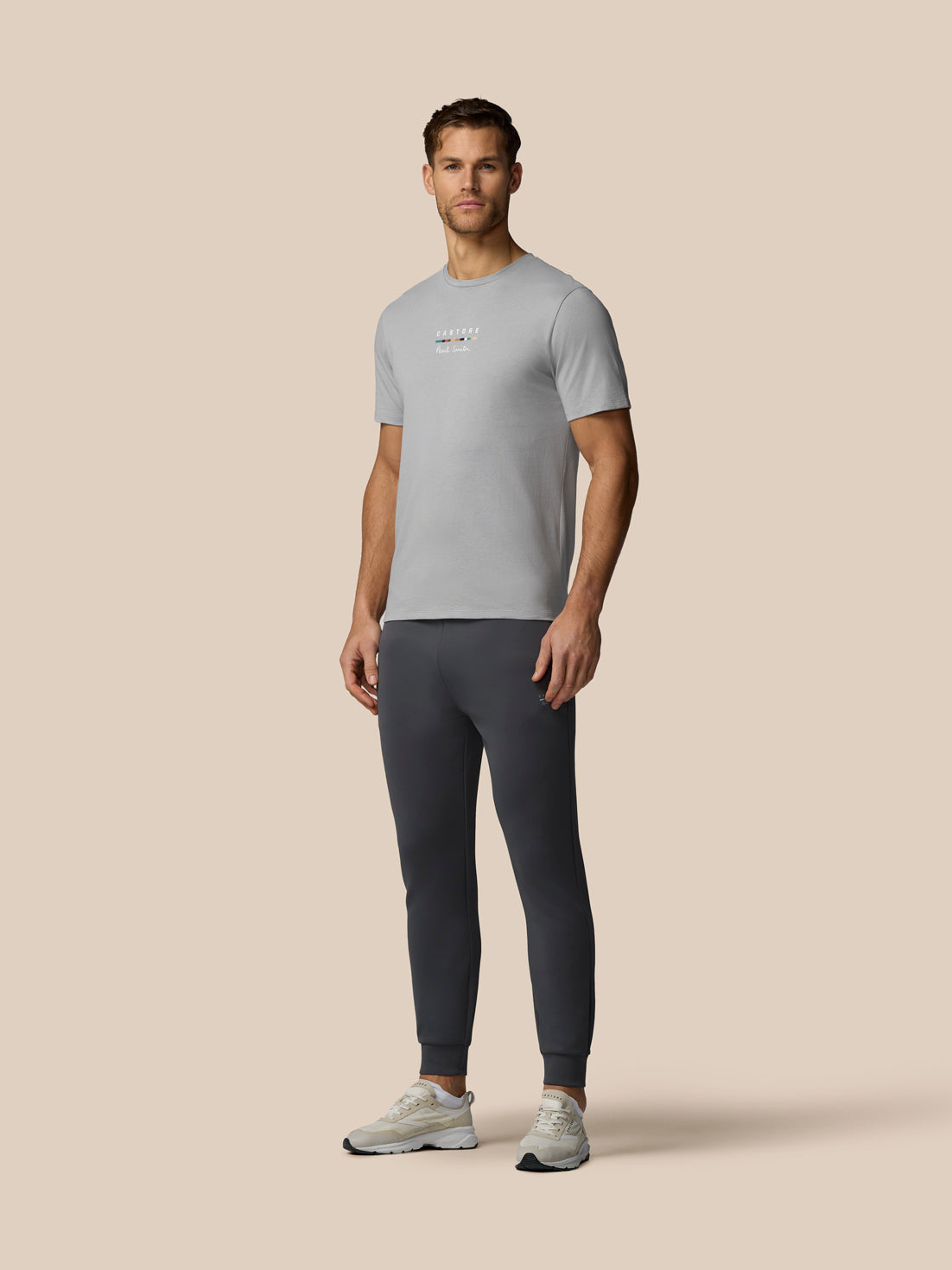 Man wearing a gray t-shirt and dark pants on a beige background