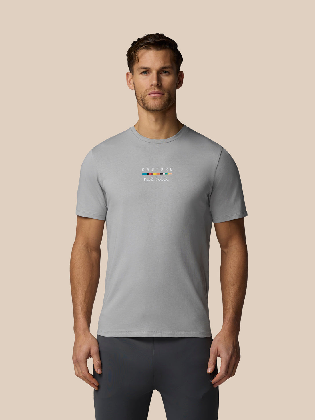 Man wearing a gray t-shirt with a logo on a beige background