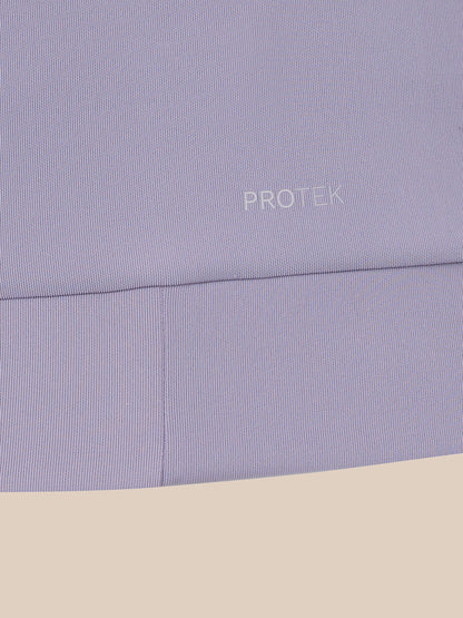 Close-up of a light lavender ribbed fabric with the word PROTEK printed in small white text, shown against a beige background.
